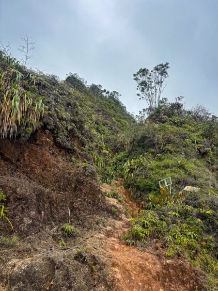 Steep, rocky terrain at Mirador San José in Guatapé, Antioquia, Colombia, with lush greenery and a cloudy sky overhead.