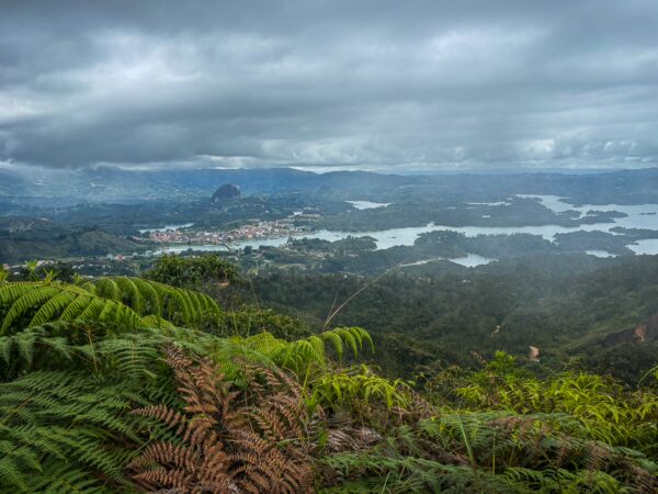 Stunning view from Mirador San José in Guatapé, Antioquia, showcasing lush greenery, calm waters, and distant mountains under moody skies.