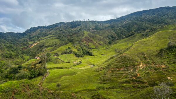 Lush green hills and valleys at Mirador San José in Guatapé, Antioquia, Colombia, under a cloudy sky.