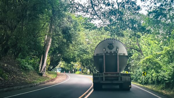 A large truck navigates a winding road surrounded by lush green trees in Honda, Tolima, Colombia.