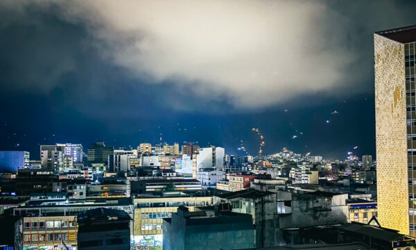 Nighttime cityscape of Ibagué, Colombia, showcasing illuminated buildings under a cloudy sky with a vibrant urban atmosphere.