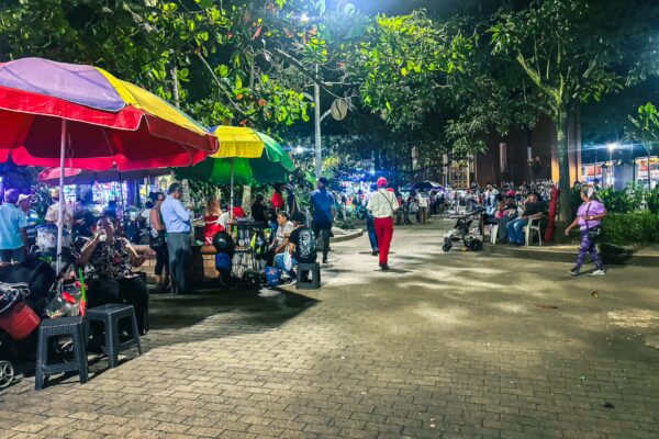 Vibrant night scene in Quindio, Colombia, with colorful vendor tents and people enjoying the lively atmosphere in the plaza.