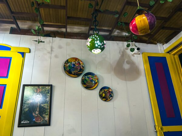 Brightly colored plates and hanging ornaments adorn a wooden wall, showcasing vibrant local artistry in Murillo, Tolima, Colombia.