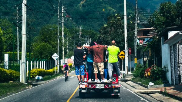 Vibrant colors of local life in Tolima, Colombia, as people ride joyfully on a truck along a scenic road.