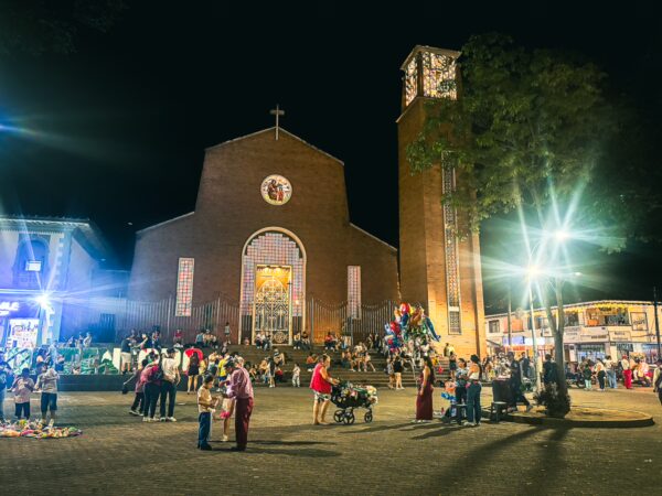 People gather at night around the vibrant square, with the illuminated church as the backdrop in Quindío, Colombia.