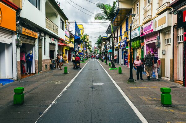 Colorful storefronts line a bustling street in Santa Rosa de Cabal, Risaralda, Colombia, with pedestrians and green planters.