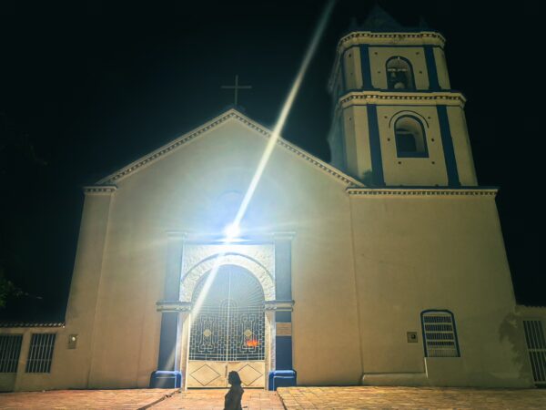 Illuminated church with a blue and white facade at night in Villavieja, Huila, Colombia, featuring a prominent bell tower.