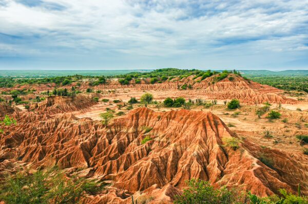Rust-colored formations and rugged terrain characterize the Tatacoa Desert in Huila, Colombia, under a dramatic sky.