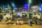 Vibrant night scene in Quindío, Colombia, featuring lively crowds, food stalls, and colorful lights.