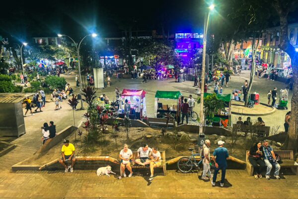 Vibrant night scene in Quindío, Colombia, featuring lively crowds, food stalls, and colorful lights.