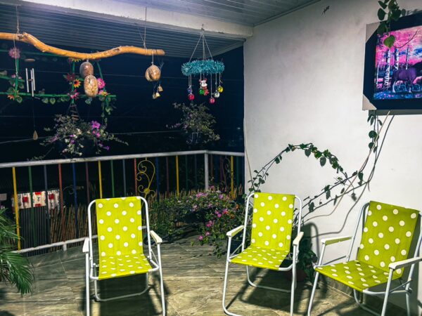 Bright green polka-dotted chairs on a cozy balcony in Villa Vieja, Huila, adorned with colorful decorations and hanging plants.