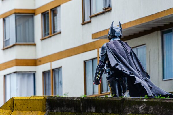 Life-size Batman statue walks along a ledge against a backdrop of modern buildings in Quindío, Colombia.