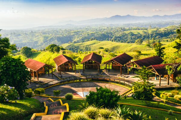 Mirador Colina Iluminada offers stunning views of lush green hills and rustic huts against the backdrop of Quindio, Colombia.