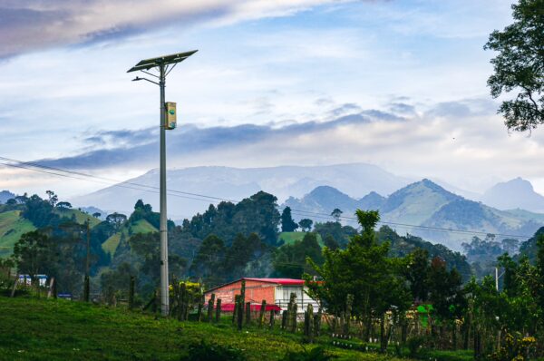 Vibrant green hills and distant mountains frame a colorful house under a cloudy sky in Tolima, Colombia.