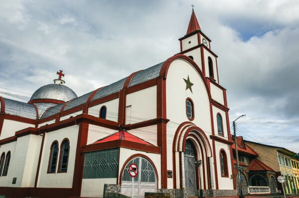 Red and white church with a star on the facade in Medellia, Milagrosa, Murillo, Tolima, Colombia against a cloudy sky.