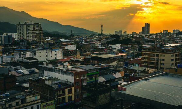 Vibrant sunset over Ibague, Tolima, revealing a sprawling cityscape of colorful buildings and distant mountains.