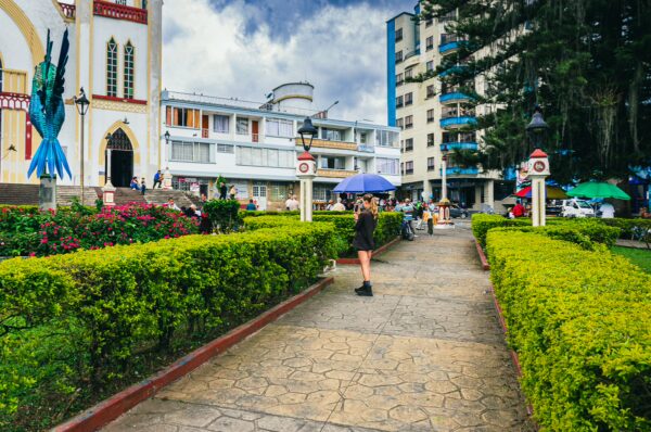 Colorful pathway lined with green hedges leads to lively Parque de Las Araucarias in Santa Rosa de Cabal, Risaralda, Colombia.