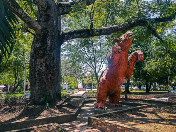 Colorful statue of a bear stands proudly under lush trees in Villavieja, Huila, Colombia, surrounded by a tranquil park setting.