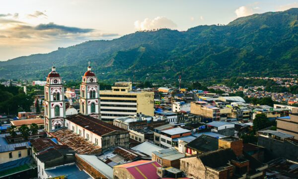 Stylish rooftops of Hotel Doral Inn contrast with the lush mountains in Ibagué, Tolima, Colombia under a vibrant sunset sky.