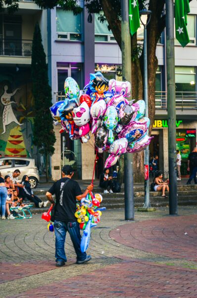 Colorful balloons fill the air at Plaza de Bolívar in Pereira, Risaralda, with people enjoying the vibrant atmosphere.