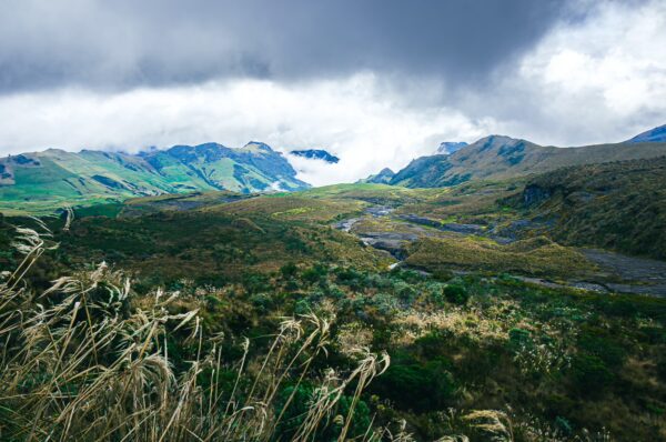 Lush green valleys and rugged mountains create a stunning backdrop at Nevado del Ruiz, Tolima, Colombia under dramatic skies.
