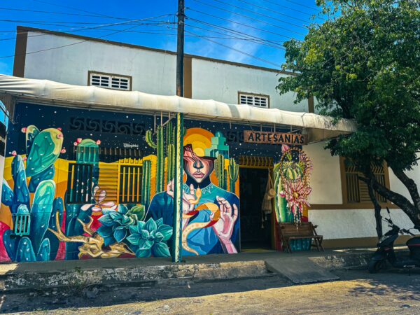 Vibrant mural featuring figures and cacti on a building in Villavieja, Huila, Colombia, showcasing local artisan culture.