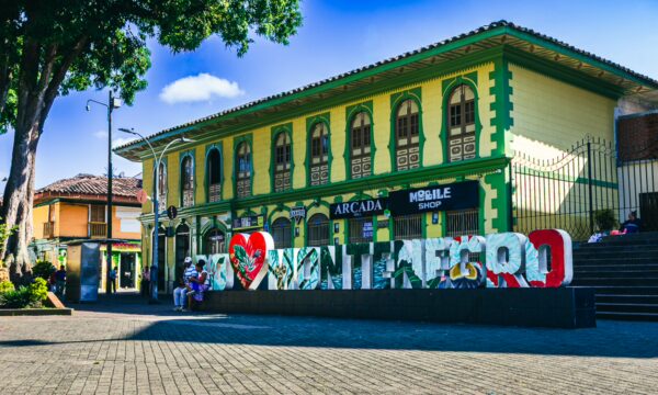Colorful street art spells out "I ❤️ Manizales" in front of traditional yellow and green architecture in Quindío, Colombia.