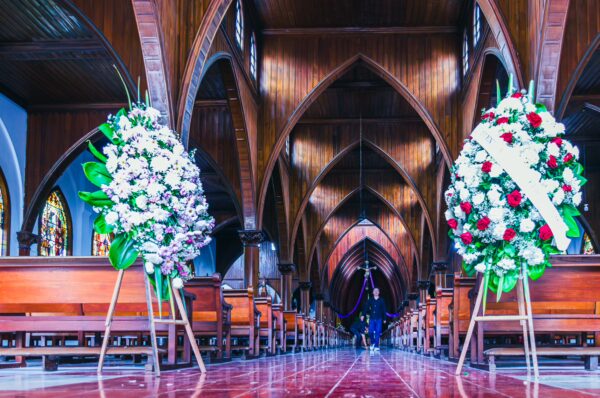 Vibrant floral arrangements flank the aisle of Nuestra Señora de las Victorias, showcasing the church's elegant wooden architecture in Santa Rosa de Cabal.