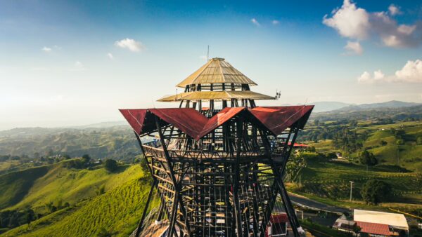 Mirador Colina Iluminada features a striking wooden structure with a distinctive red-roof design, surrounded by lush green hills in Filandia, Quindio, Colombia.
