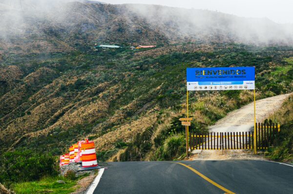 Vibrant road leads to Nevado del Ruiz, flanked by orange traffic cones and misty mountains in Tolima, Colombia.