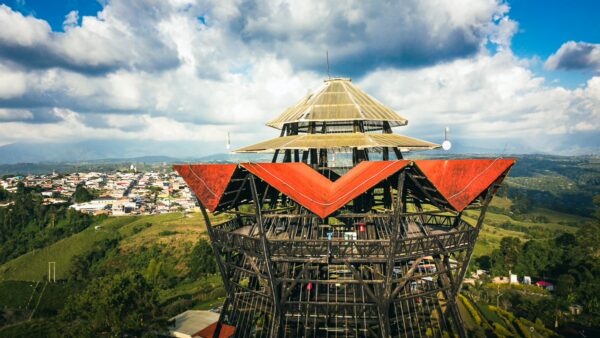 Mirador Colina Iluminada features a striking wooden observation tower with vibrant red roofs, overlooking the green hills of Filandia, Quindío.