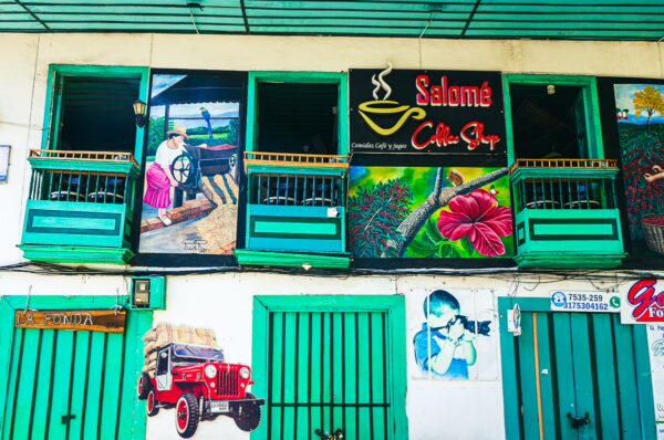 Colorful murals decorate a building exterior in Quindio, Colombia, showcasing local culture with vibrant greens and artistic designs.