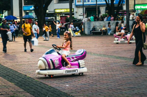 Colorful kids' ride in Plaza de Bolívar, Pereira, with children playing and pedestrians enjoying the vibrant atmosphere.
