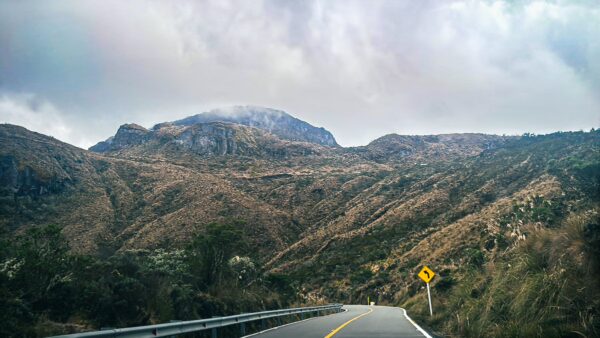 Winding road through scenic mountainous terrain near Nevado del Ruiz, showcasing rugged hills and cloudy skies in Tolima, Colombia.