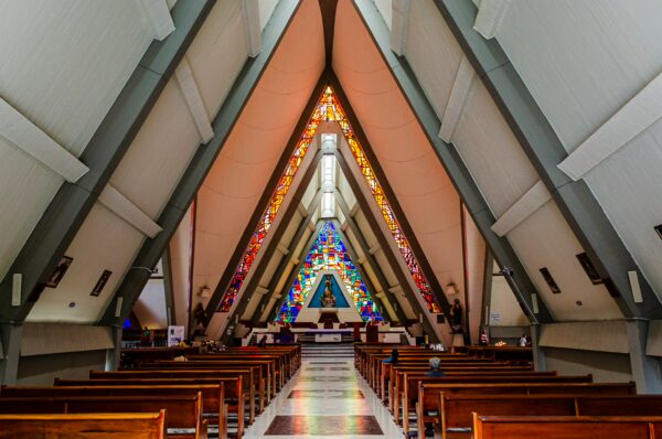 Stunning interior of the Cathedral Immaculada Concepción in Armenia, Quindío, showcasing vibrant stained glass and wooden pews.