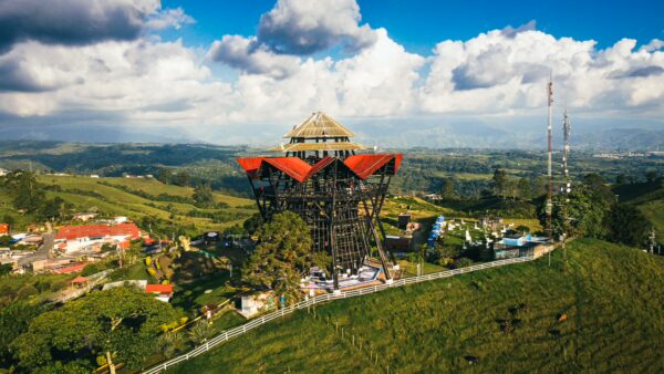 Mirador Colina Iluminada features a striking multi-tiered structure with red roofs, surrounded by lush green hills in Filandia, Quindio, Colombia.