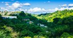 Lush green valleys and colorful houses nestled among the hills of Quindio, Colombia, under a bright blue sky.