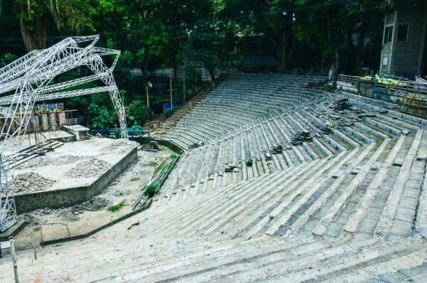 Stone seating steps and a partially constructed stage set against lush greenery at Parque Centenario in Ibagué, Tolima, Colombia.