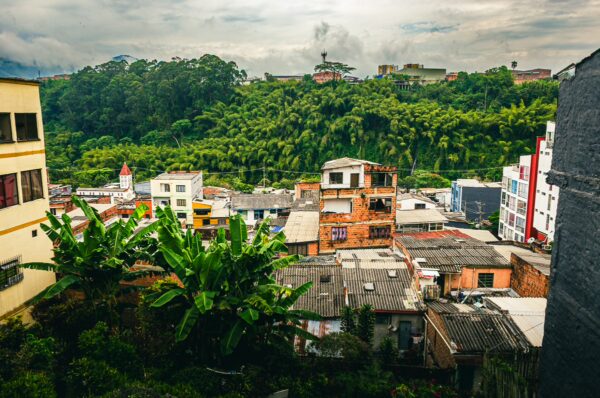 Vibrant buildings and lush greenery reflect the landscape of Pereira, Risaralda, Colombia, under a cloudy sky.