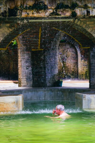 Relaxing in the warm thermal waters of Termales Rosa, surrounded by rustic arches and lush greenery in Risaralda, Colombia.