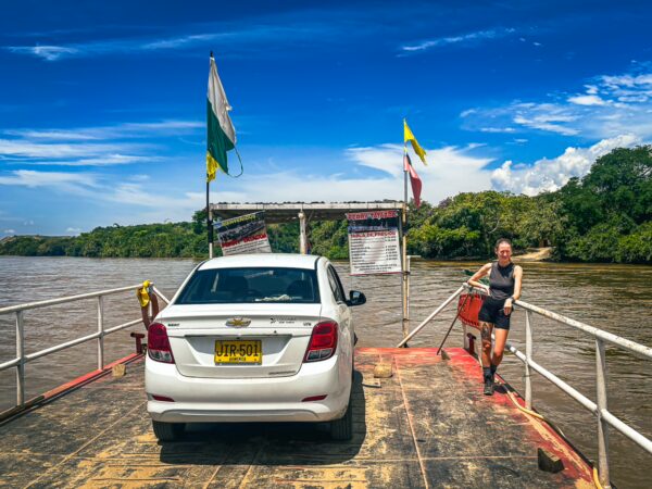Car on a ferry crossing the river in Villavieja, Huila, Colombia, under a vibrant blue sky with scattered clouds.