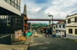 Viaducto de Pereira arches over a vibrant street in Risaralda, Colombia, with yellow taxis and colorful buildings lining the road.