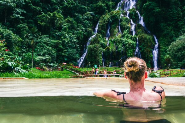 Relaxing in natural hot springs surrounded by lush greenery and a waterfall at Termales de Santa Rosa, Risaralda, Colombia.
