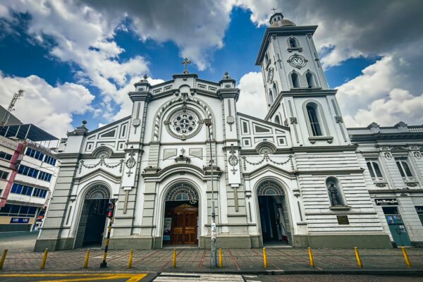 White façade of the Cathedral in Ibagué, Tolima, Colombia, showcasing intricate architectural details under a cloudy sky.