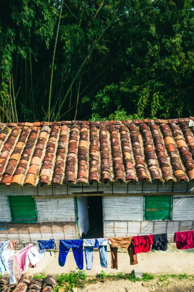 Rustic house with a tile roof and green window shutters in Montenegro, Quindio, Colombia, featuring clothes drying on a line.