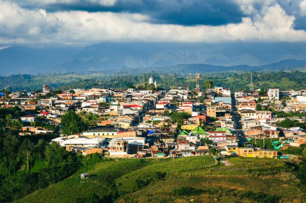 Colorful rooftops and lush green hills stretch across the landscape at Mirador Colina Iluminada in Filandia, Quindio, Colombia.