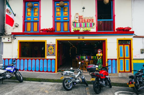 Colorful building façade featuring vibrant doors and a lively entrance in Santa Rosa de Cabal, Risaralda, Colombia. Motorcycles parked nearby.