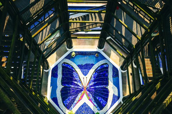 Vibrant butterfly mosaic at the Mirador Colina Iluminada in Filandia, Quindío, Colombia, surrounded by a striking metal structure.