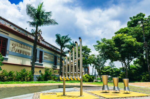 Elegant musical sculptures stand in Parque de la Música, surrounded by lush greenery and a vibrant sky in Ibague, Tolima, Colombia.