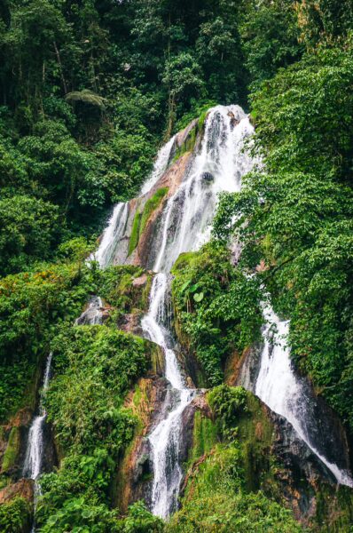 Lush green landscapes surround cascading waterfalls at Termales Rosa in Risaralda, Colombia, creating a serene natural retreat.